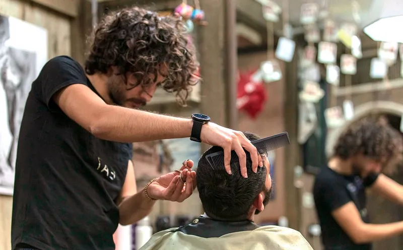 Barbero realizando un corte con máquina a un cliente